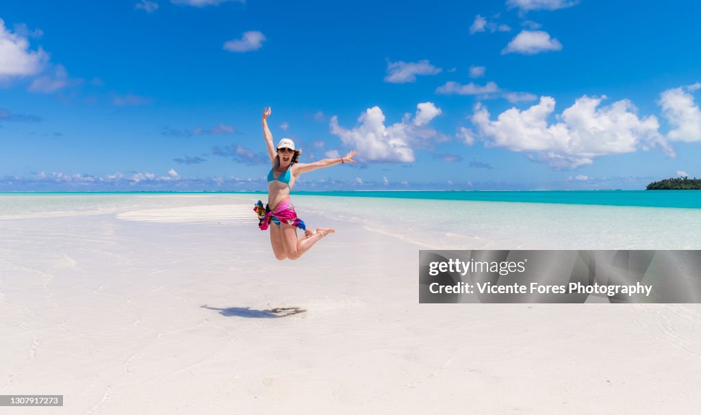 Girl walking with a sarong on an amazing sunny day at one foot island in the lagoon of Aitutaki