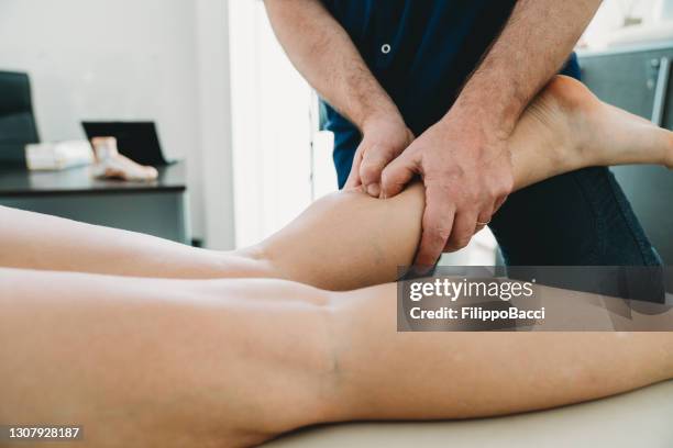 chiropractische arts die het kalf van een jonge vrouw manipuleert - kuit menselijk been stockfoto's en -beelden