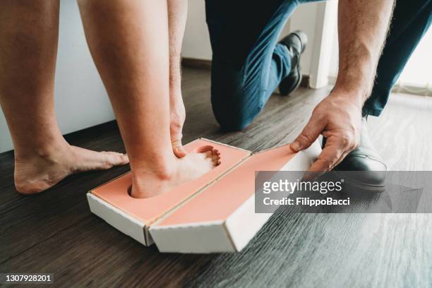 de arts neemt de voetafdrukken van een jonge vrouw om nieuwe schoenzolen te bouwen om haar houding te helpen verbeteren - soles pose stockfoto's en -beelden