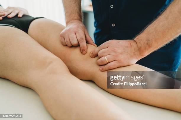 chiropractic doctor manipulating the knee of a young woman - knee length stock pictures, royalty-free photos & images