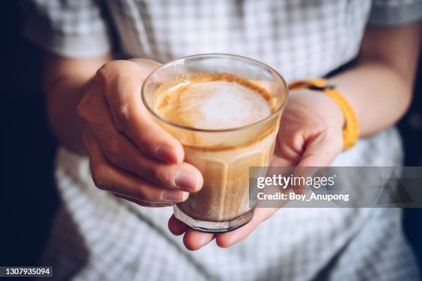 close up of woman hand holding a cup of dirty latte before drink it. - women drinking coffee photos et images de collection