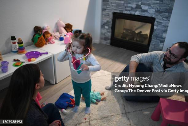 Emmie Beck center, exams her parentsis Nina left, and Derek toy medical kit after daycare for the first time since she became sick with MIS-C at her...