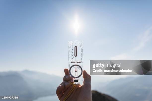 human hand with compass, sunny sky in background - compass north foto e immagini stock