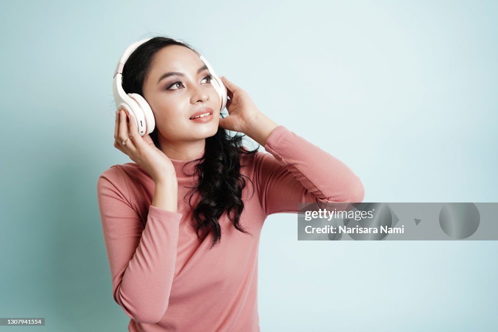 Happy Asian teenage girl listen the music song in wireless headphone from mp3 player technology. relaxation and music lover concept.