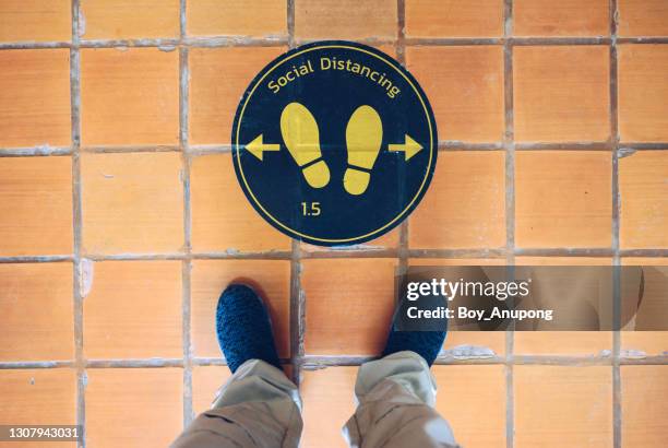 high angle view of someone foot standing on the social distancing sticker marking. - social distancing fotografías e imágenes de stock