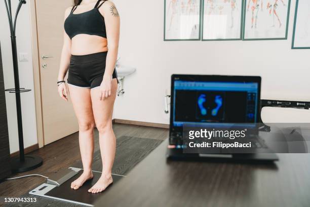 la giovane donna adulta è in piedi su uno scanner a pressione medica per analizzare la sua impronta e realizzare nuove solette per scarpe per migliorare la sua postura - scanner medico foto e immagini stock