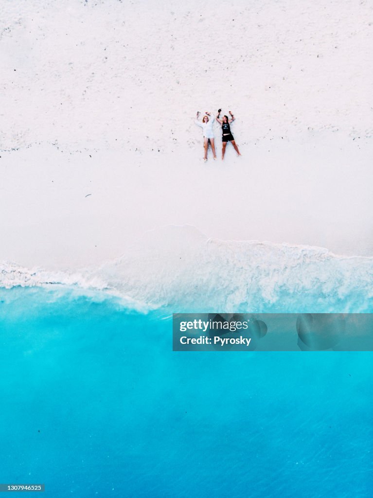 Couple lies on a beautiful white sandy beach in summer