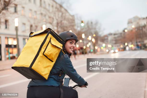 a delivery biker looking over their shoulder. - bicycle courier stock pictures, royalty-free photos & images