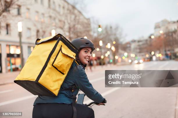 a delivery biker looking over their shoulder. - entregar imagens e fotografias de stock