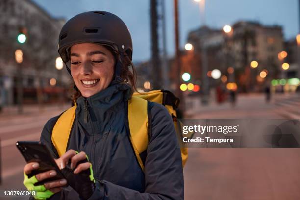 one delivery woman looking at her phone. - night delivery stock pictures, royalty-free photos & images