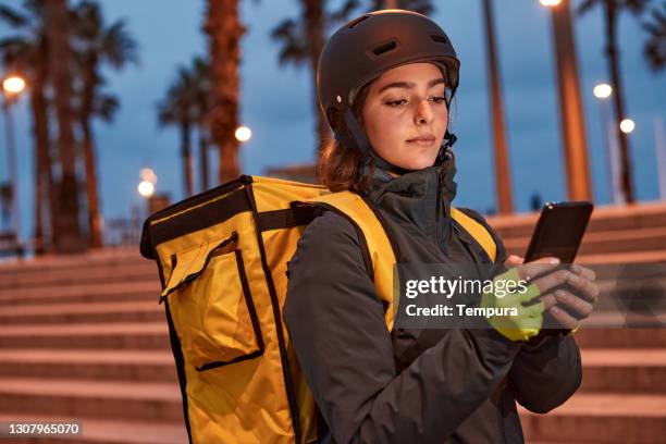 a female delivery biker with a phone. - bicycle messenger stock pictures, royalty-free photos & images