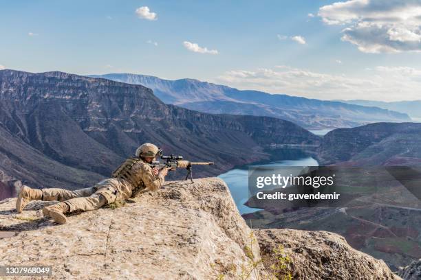 francotirador del ejército apuntando a su objetivo en la cima del acantilado - francotirador fotografías e imágenes de stock