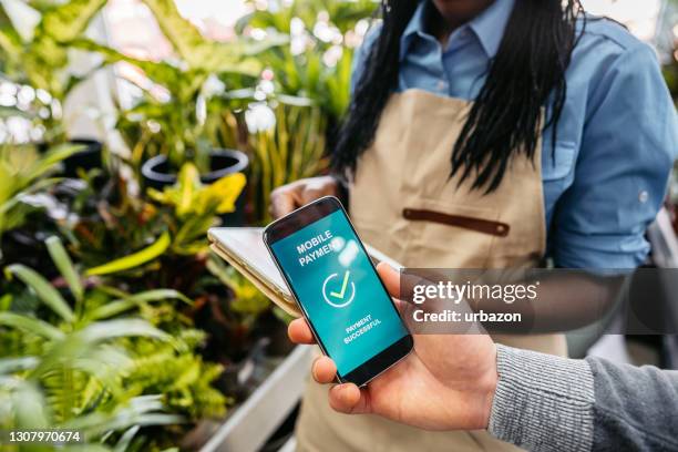 contactless payment in garden center - customers pay with contactless cards imagens e fotografias de stock