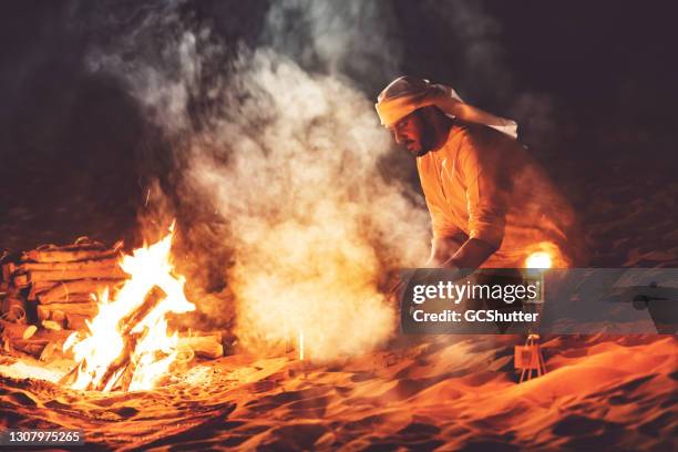 homme arabe commençant un gril de kebab à un camp de désert - arabian desert adventure night photos et images de collection