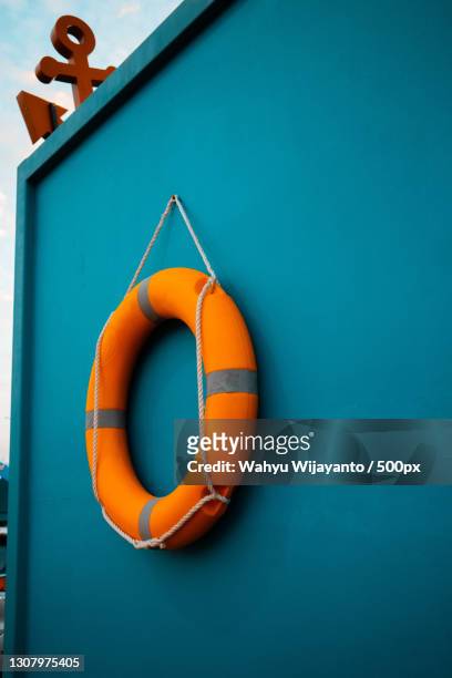 close-up of life belt hanging against blue wall - rettungsring stock-fotos und bilder