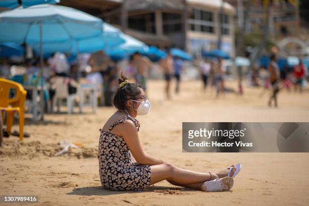 Tourist in a bathing suit wearing a mask is seen sitting on the sand of Caleta beach, which has no restrictions amid the coronavirus pandemic on...