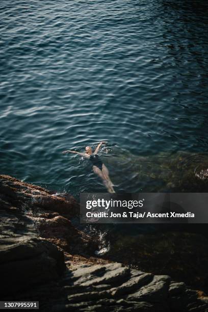 young woman floats on back in calm sea - acostado de espalda fotografías e imágenes de stock