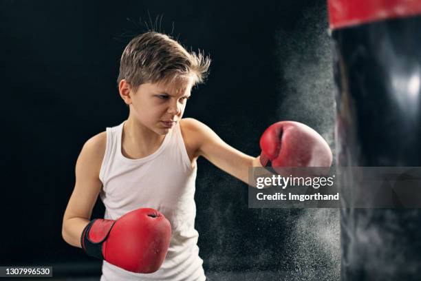 kleiner junge trainiert boxen mit boxsack - boy in hard hat stock-fotos und bilder