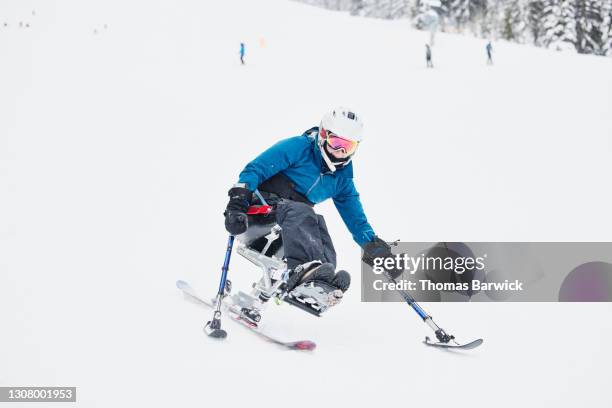 full length view of female adaptive athlete on monoski skiing on winter morning - sitski stockfoto's en -beelden