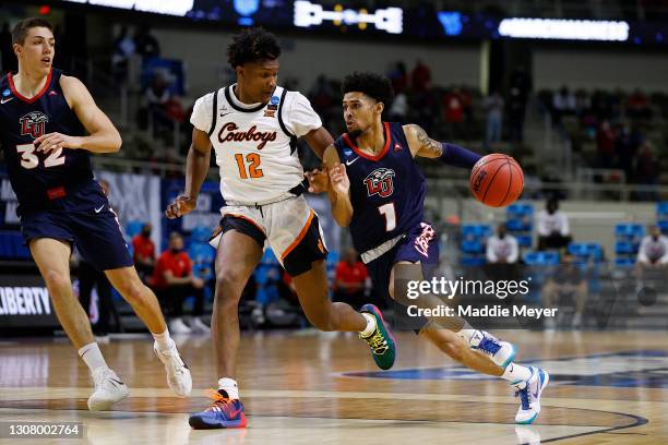 Chris Parker of the Liberty Flames drives past Matthew-Alexander Moncrieffe of the Oklahoma State Cowboys during the first half in the first round...