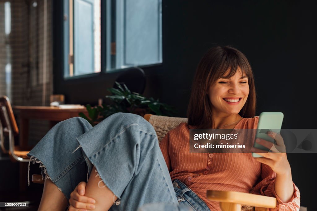 Women in Business: Beautiful Smiling Young Businesswoman Using a Mobile Phone while Sitting Casually in a Chair