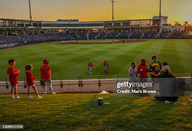 Mother takes a photo of her children posing with a home run ball they caught while Victor Robles and Gerardo Parra of the Washington Nationals pose...