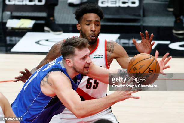 Luka Doncic of the Dallas Mavericks loses control of the ball while pressured by Derrick Jones Jr. #55 of the Portland Trail Blazers during the...