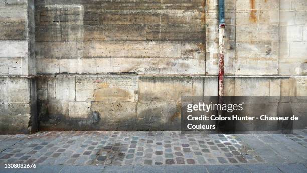 antique and empty stone wall with pipe and paved sidewalk in paris - trottoir paris stock-fotos und bilder