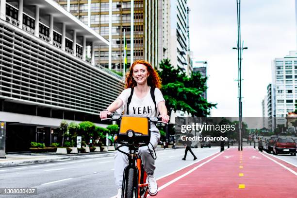 una mujer sonriendo mientras montaba en bicicleta en são paulo - avenida paulista fotografías e imágenes de stock