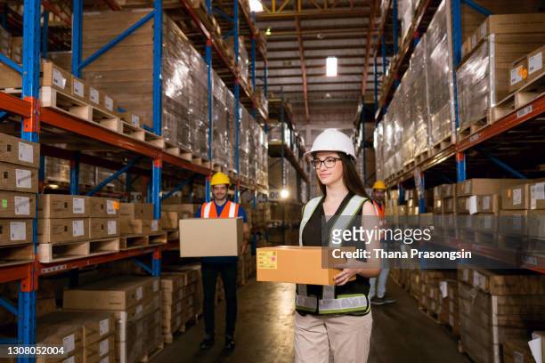 woman working at a warehouse. carrying boxes - safety equipment stock pictures, royalty-free photos & images
