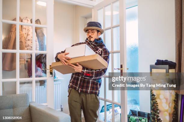 young handsome asian man receiving home delivered parcels in new house - carrying box stock pictures, royalty-free photos & images