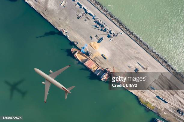 airplane flying above cargo ship. - air freight transportation stock pictures, royalty-free photos & images