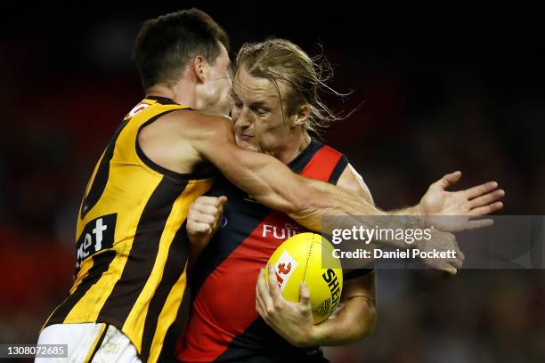 Mason Redman of the Bombers is tackled by Jaeger O'Meara of the Hawks during the round one AFL match between the Essendon Bombers and the Hawthorn...