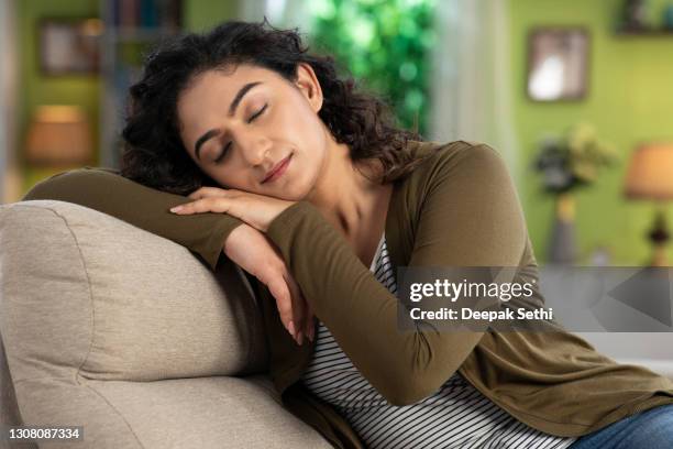 shot of a young women sitting on sofa:- stock photo - dozes stock pictures, royalty-free photos & images