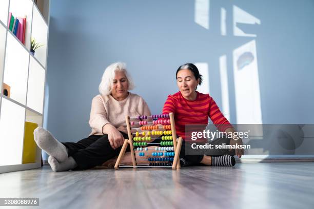 madre anziana e figlia adulta matura usando abacus - gerontology foto e immagini stock