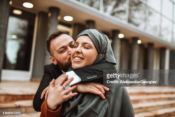 moderne muslimische männliche küssen schöne frau tragen hijab draußen - islam stock-fotos und bilder