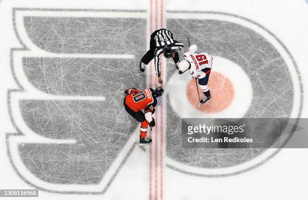 Linesman Julien Fournier prepares to drop the puck on a face-off between Andy Andreoff of the Philadelphia Flyers and Nicklas Backstrom of the...