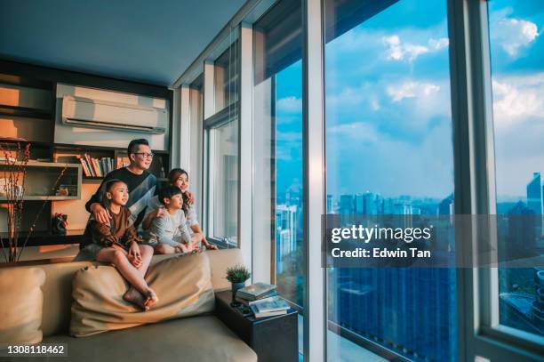 asian chinese family with 2 children looking through window enjoying beautiful sunset at living room in kuala lumpur city - malaysia building stock pictures, royalty-free photos & images