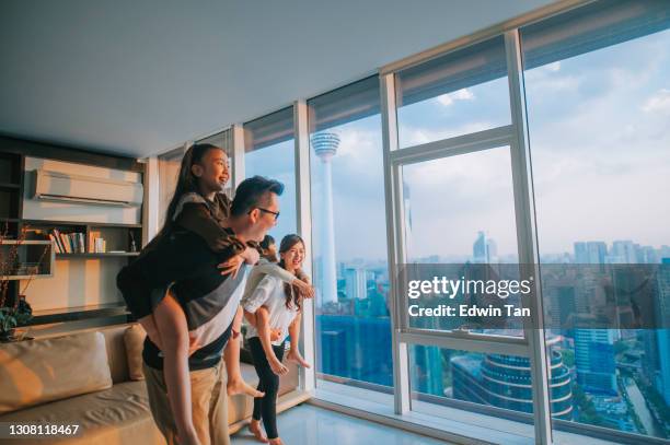 aziatische chinese familie met 2 kinderen piggyyback spelen in woonkamer in kuala lumpur stad - malaysia father and son stockfoto's en -beelden