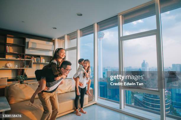 famiglia cinese asiatica con 2 bambini piggyyback giocare in soggiorno nella città di kuala lumpur - condizionatore casa foto e immagini stock