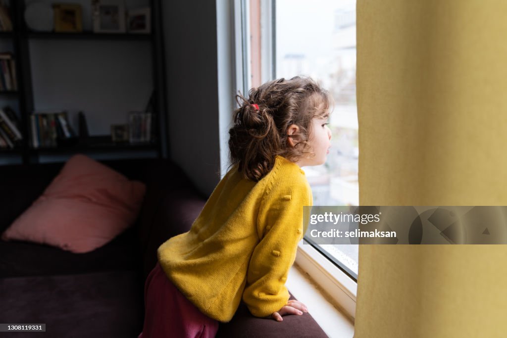 Portrait Of Cute Toddler Girl Looking Through Window
