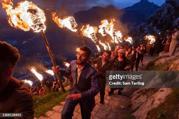 Iraqi Kurds carry lit torches up Kali mountain to celebrate Nowruz, the Persian new year, on March 20, 2021 in Akre, Iraq. The Persian New Year is an...