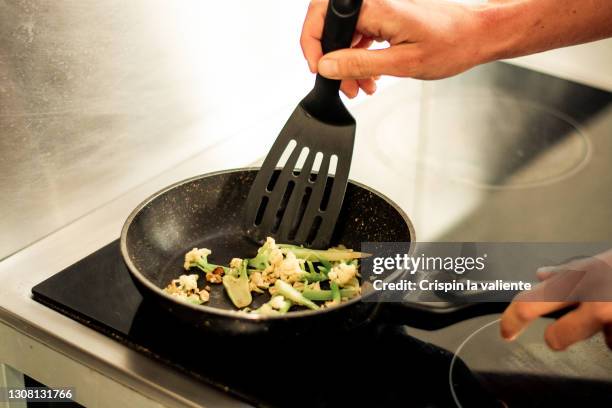 close-up of frying pan with cauliflower on glass ceramic - küchenspatel stock-fotos und bilder