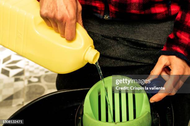 close-up of bleach pot pouring into a bucket - daily bucket photos et images de collection