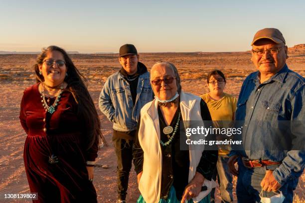 de gelukkige glimlachende inheemse amerikaan, navajo familie verzamelt zich buiten hun huis in het stammenpark van de vallei van het monument, utah dichtbij zonsondergang - native american reservation stockfoto's en -beelden