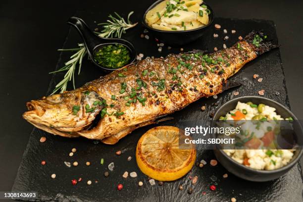 baked perch fish isolated on blacstand with lemon rosemary and salad - perch fish stock pictures, royalty-free photos & images