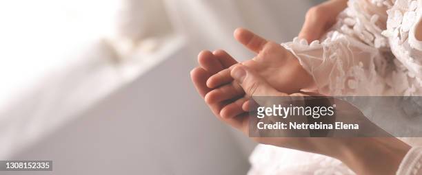 a small child's hand in the mother's hand on a light background. the sign for the banner. the tenderness of a mother, the love of a child. the future is in children - baby background stock pictures, royalty-free photos & images