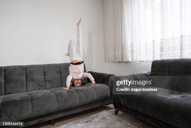 petite fille mignonne faisant des handstands sur le sofa - acrobatic activity photos et images de collection