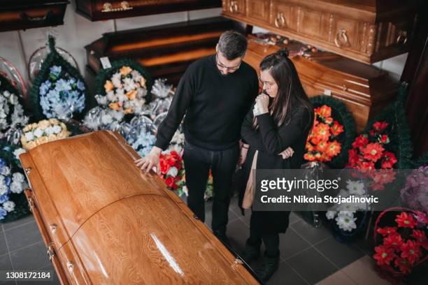 undertaker zeigt einer witwe särge und kreuze - funeral grief flowers stock-fotos und bilder