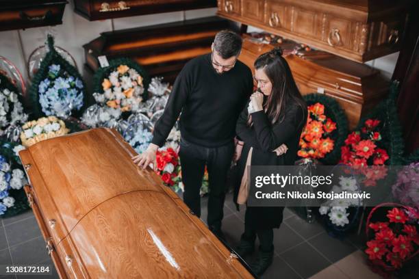 begrafenisondernemer die doodskisten en kruisen aan een weduwe toont - funeral parlor stockfoto's en -beelden